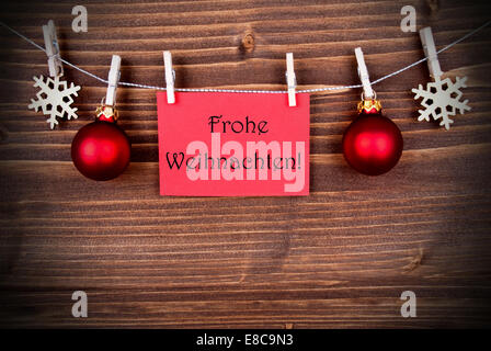Red Banner with the German Words Frohe Weihnachten which means Merry Christmas Hanging on a Line, German Christmas Greetings Stock Photo