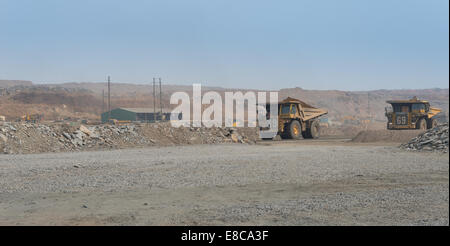 Two mining dump trucks transport copper ore from an open cast mine to the beneficiation plant in an African copper mine. Stock Photo