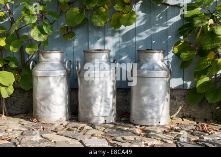 three churns for milk with plants and wood as background Stock Photo