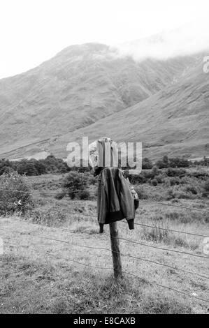 vintage leather jacket hanging over a fence pole in the highlands Stock Photo