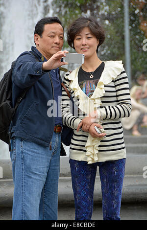 An Asian couple taking a selfie near the fountain in Washington Square Park in Greenwich Village, New York City Stock Photo