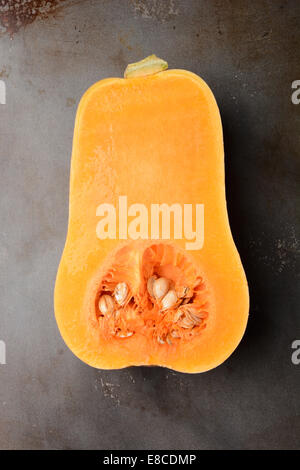 Butternut Squash on a metal cooking sheet. The vegetable is cut in half showing the inside. Vertical format. Stock Photo