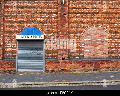 Bricked up window with closed entrance on factory building UK Stock Photo