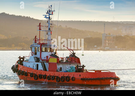 Red tug is underway on Black sea, Varna harbor, Bulgaria Stock Photo