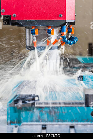 A water-cooled CNC milling cutter 'in action' while producing a custom aluminum spare part Stock Photo