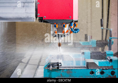 A water-cooled CNC milling cutter 'in action' while producing a custom aluminum spare part Stock Photo