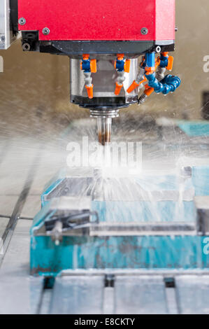 A water-cooled CNC milling cutter 'in action' while producing a custom aluminum spare part Stock Photo