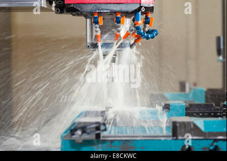 A water-cooled CNC milling cutter 'in action' while producing a custom aluminum spare part Stock Photo