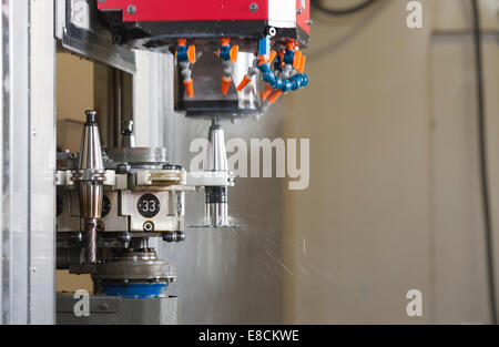 A CNC milling cutter is automatically changing its tooltip during production of a custom aluminum spare part Stock Photo