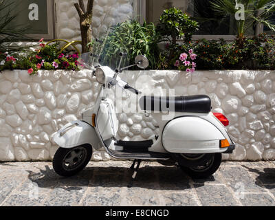 White scooter parked against a white wall Stock Photo