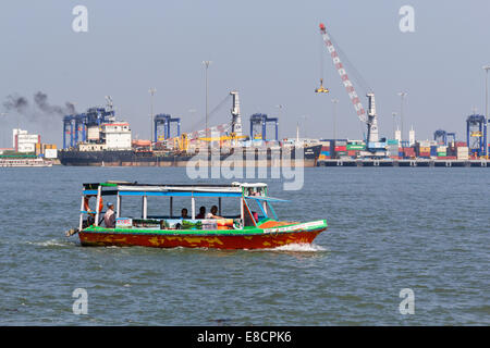 BOAT TAXI PORT KOCHI OR  COCHIN INDIA WITH OCEAN VESSEL BEING LOADED AT THE NEW CONTAINER PORT Stock Photo