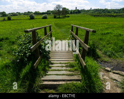 Footbridge across small stream in field Stock Photo