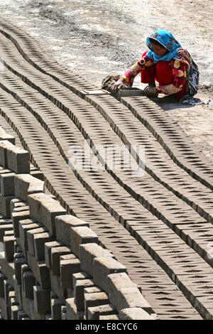 female brickyard worker form clay bricks on a field of the Patoki Brick Kiln near Lahore, Pakistan Stock Photo