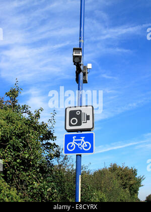 A traffic monitoring camera mounted on a post above the road together with information signs Stock Photo