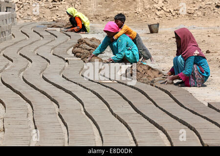 female brickyard worker form clay bricks on a field of the Patoki Brick Kiln near Lahore, Pakistan Stock Photo