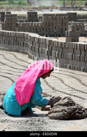 female brickyard worker form clay bricks on a field of the Patoki Brick Kiln near Lahore, Pakistan Stock Photo