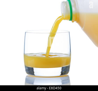 Pouring fresh orange juice, from gallon container, into glass on white with reflection Stock Photo