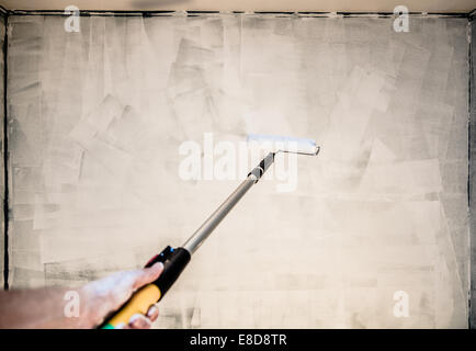 POV of Someone Painting the Wall with Roller Pin Stock Photo
