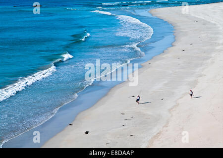 Couple walking barefoot along beautiful sandy beach at the water's edge, warm summer sunshine, Balnakeil Bay Sutherland Scotland Stock Photo