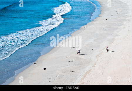 Couple walking barefoot along beautiful sandy beach at the water's edge, warm summer sunshine, Balnakeil Bay Sutherland Scotland Stock Photo