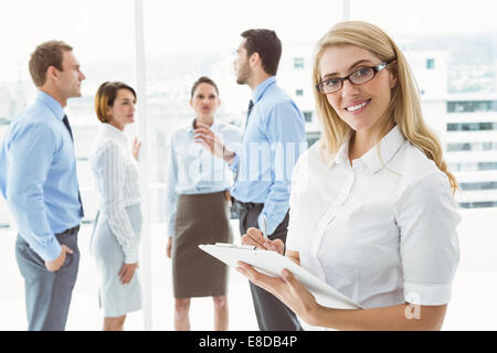 Businesswoman writing notes with colleagues behind Stock Photo