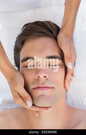 Man receiving facial massage at spa center Stock Photo