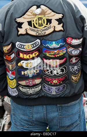 Biker wearing a leather jacket covered in Harley Owners Group badges Stock Photo
