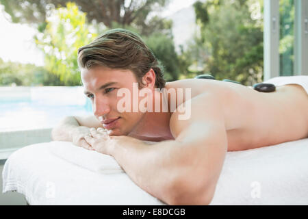 Handsome man receiving stone massage at spa center Stock Photo