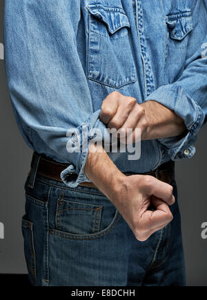 Man in denim shirt rolling up his sleeves Stock Photo