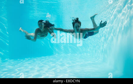 Couple holding hands and swimming underwater Stock Photo