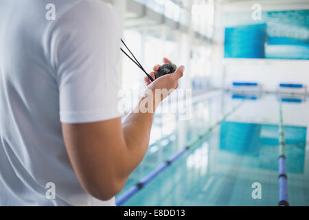 Swimming instructor holding stopwatch by the pool Stock Photo