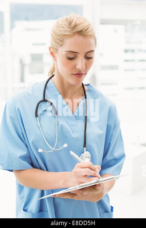 Concentrated female doctor writing on clipboard Stock Photo