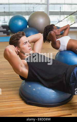 Couple doing sit ups on exercise balls Stock Photo