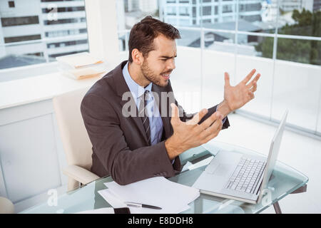 Frustrated businessman using laptop in office Stock Photo