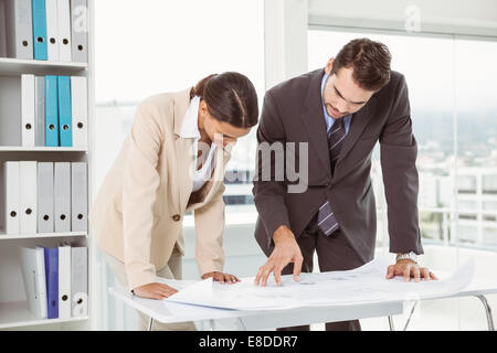 Colleagues working on blueprints at office Stock Photo