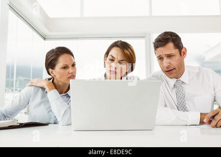 Three young business people using laptop at office desk Stock Photo