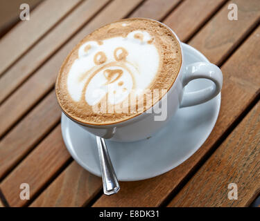 Teddy bear latte art coffee cup on a wooden table Stock Photo