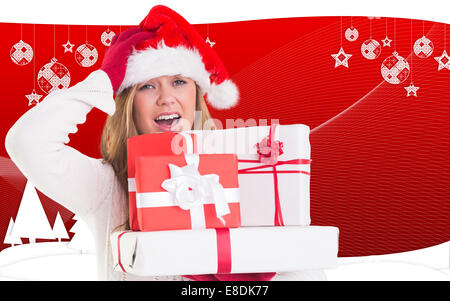 Composite image of festive blonde holding pile of gifts Stock Photo