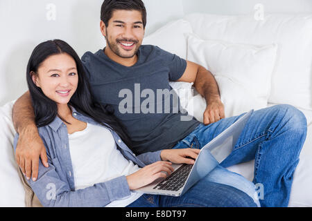 Asian Chinese couple relaxing using laptop computer on sofa home Stock Photo