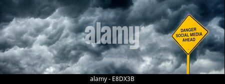 A road sign that reads "Danger Social Media Ahead" against dark and ominous storm clouds. Stock Photo