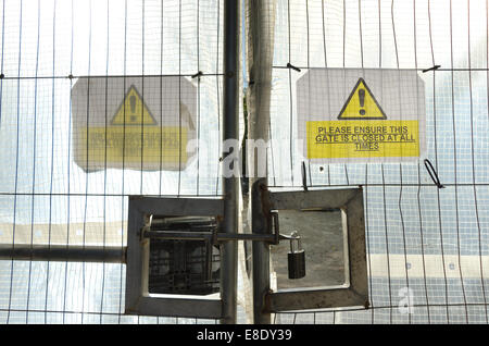 Hidden from view behind metal railings and translucent plastic screen locked gates bar access to dangerous plant machinery H&S Stock Photo