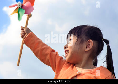 cute little girl on grass in summer day holds windmill for adv or others purpose use Stock Photo