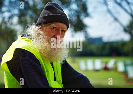 A man with a long gray beard sitting on a bike with high visibility vest on Stock Photo