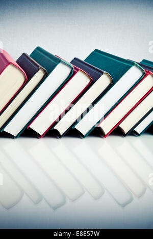Red, black and green books in a row on white reflective surface Stock Photo