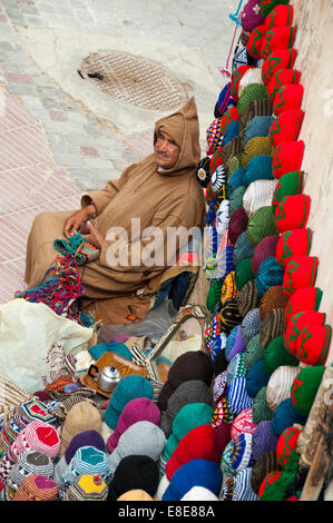 Vertical portrait of a Moroccan man knitting headwear at his stall in Essaouira Stock Photo
