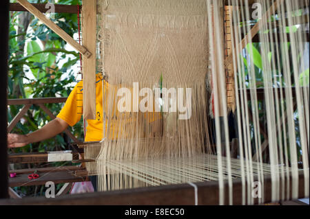 Woman weaving silk in traditional way at manual loom. Laos Stock Photo