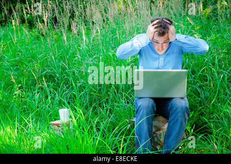 Despaired man outdoors with a cup and laptop Stock Photo