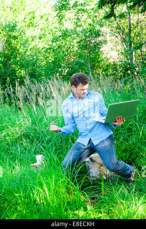 Super happy man in the forest with a laptop... it's a sucess ! Stock Photo