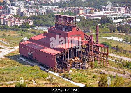 View from above derelict empty factory at Italsider steelworks industrial building with apartment housing beyond Bagnoli Naples Napoli Campania Italy Stock Photo