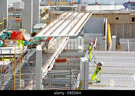 Building construction site work in progress workers in high visibility jacket & hard hat worker & crane positioning concrete floor panel London UK Stock Photo